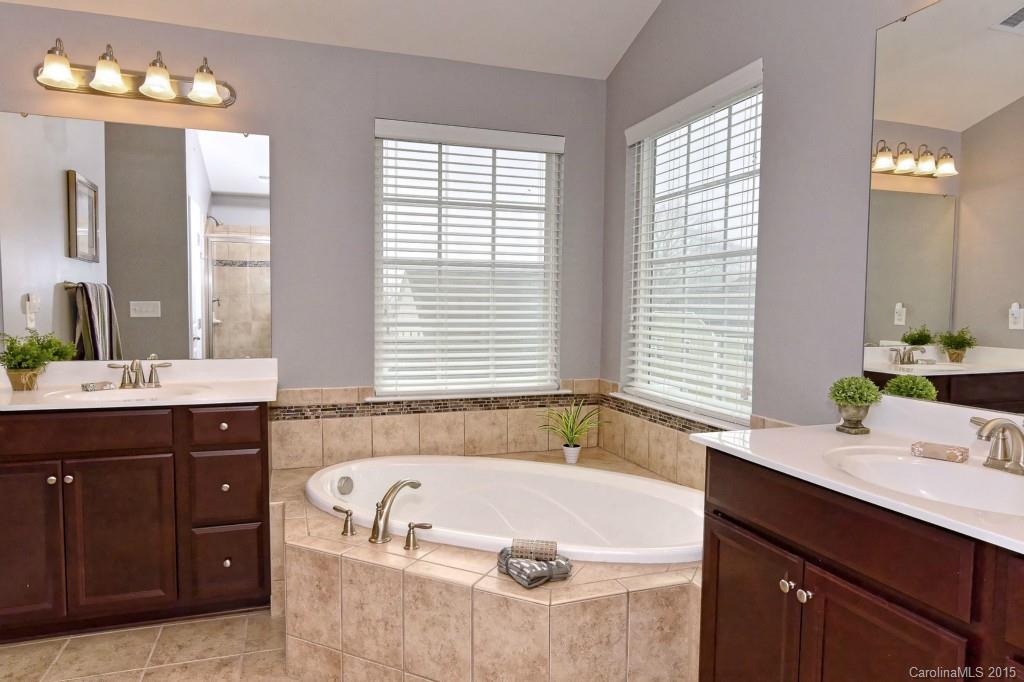 1621 Ridgehaven Road, Unit 240 Waxhaw, NC 28173 - Photo 13 of 24 a bathroom with a tub a double vanity sink a window and a mirror