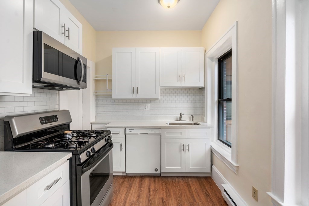 857 Beacon Street, Unit 23 Boston, MA 02215 - Photo 11 of 15 a kitchen with stainless steel appliances a sink dishwasher a microwave oven and cabinets with wooden floor