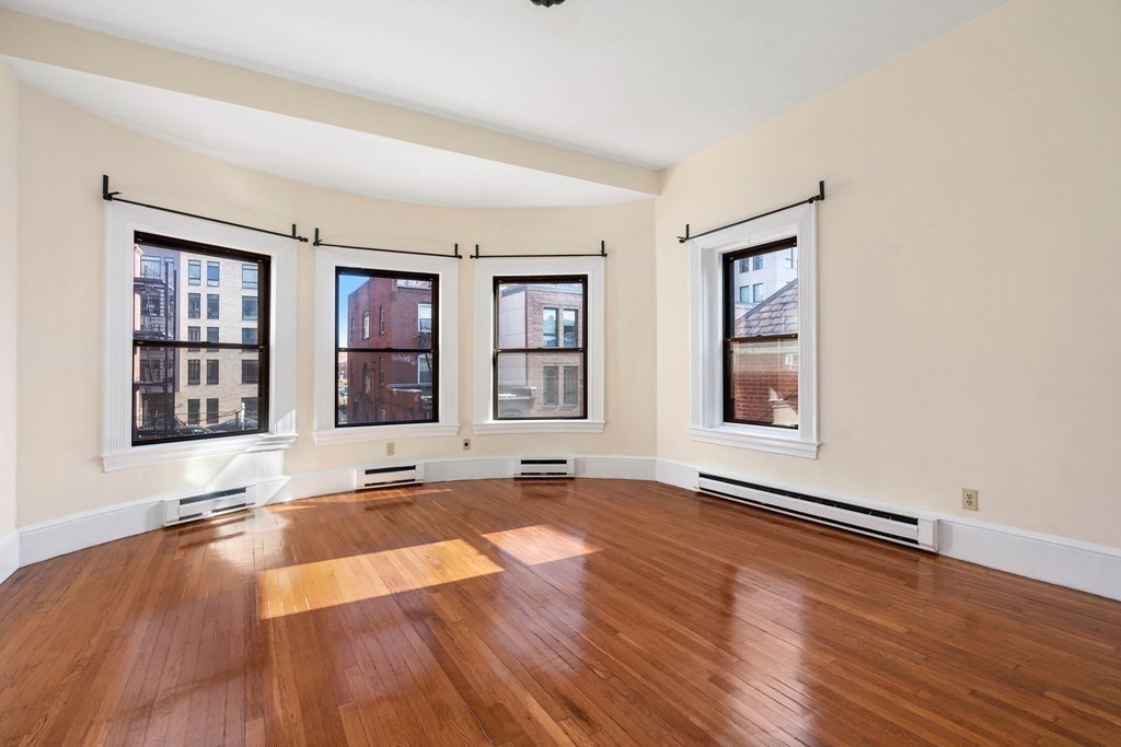 857 Beacon Street, Unit 23 Boston, MA 02215 - Photo 4 of 15 an empty room with window and wooden floor