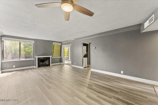 a view of an empty room with a window and wooden floor