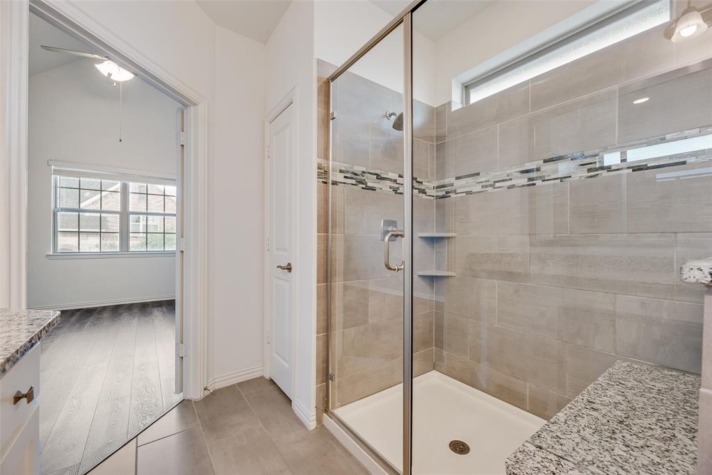 4670 I Rhett Lane, Unit I Carrollton, TX 75010 - Photo 21 of 31 Glass-enclosed shower with tile surround, built-in shelving, and a granite-finish bench