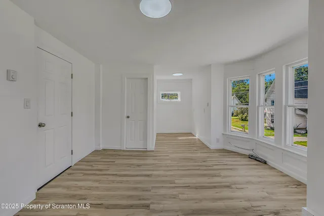 a view of an empty room with window and wooden floor