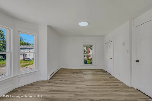 a view of an empty room with window and wooden floor
