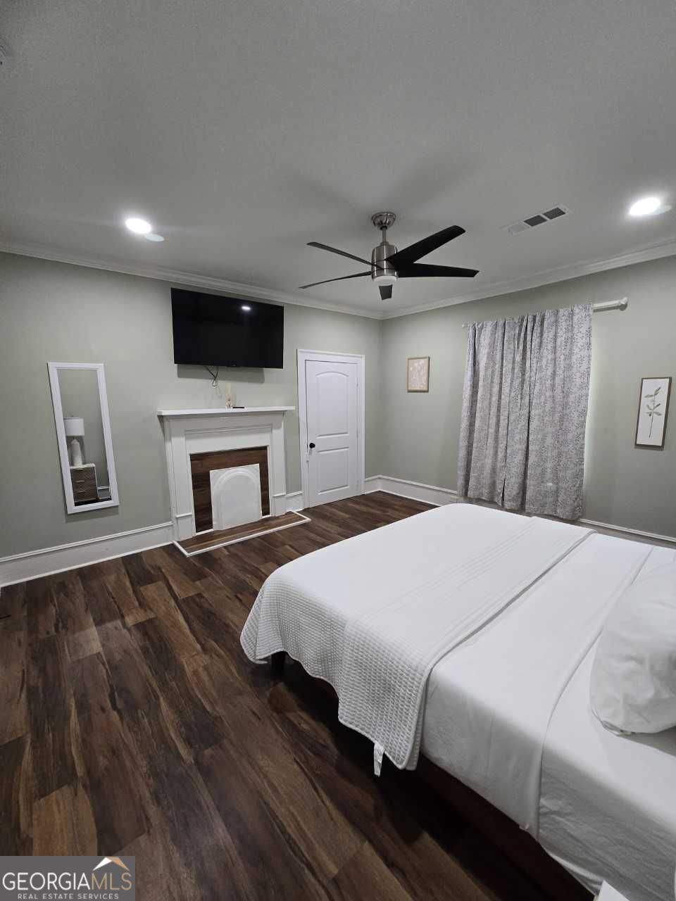 402 Meriwether Street Griffin, GA 30224 - Photo 19 of 36 a bedroom with a large bed a flat tv screen and a fireplace
