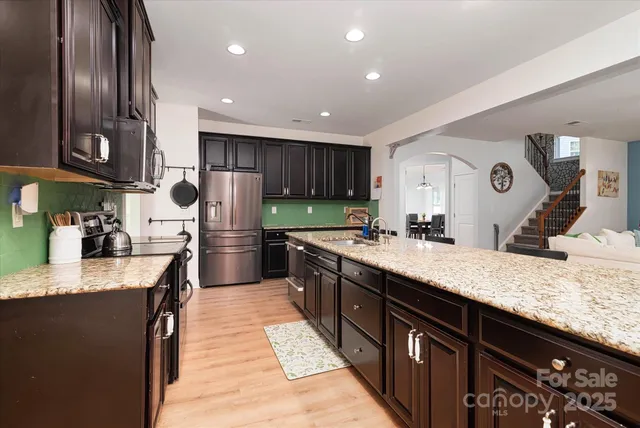 a kitchen with stainless steel appliances granite countertop a stove a sink and a microwave
