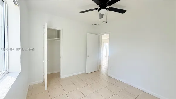 a view of an empty room and chandelier fan