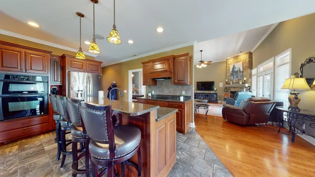 a dining room with stainless steel appliances kitchen island granite countertop a table chairs and a refrigerator