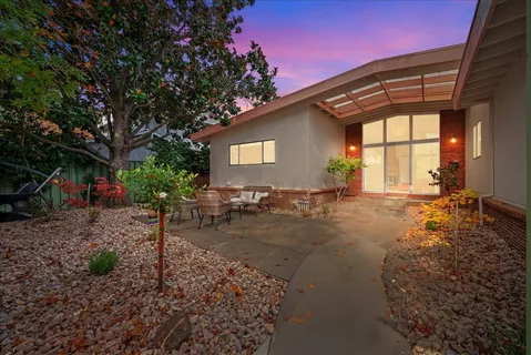 a backyard of a house with table and chairs under an umbrella