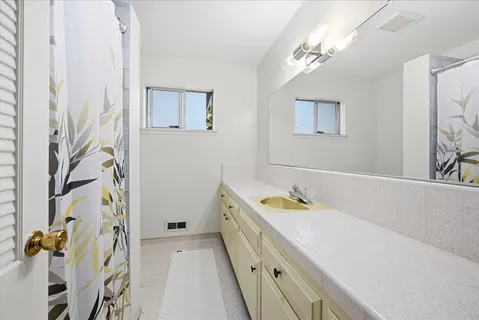 a spacious bathroom with a granite countertop sink a mirror a vanity and a shower