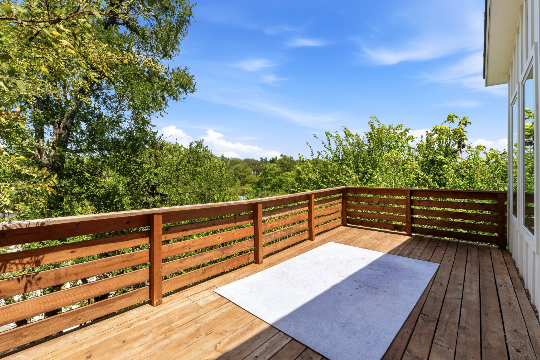 5010 Baker Street Austin, TX 78721 - Photo 21 of 22 An elevated wood balcony overlooks dense green treetops under a clear blue sky.