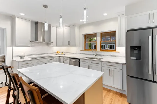 a kitchen with kitchen island a stove a sink a refrigerator and chairs