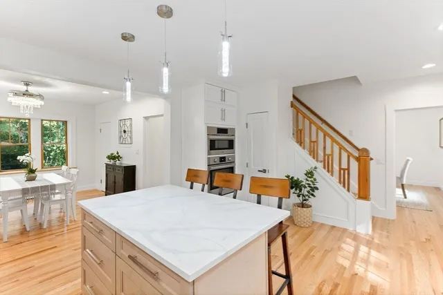 a view of kitchen with kitchen island a stove a refrigerator and a dining table with wooden floor