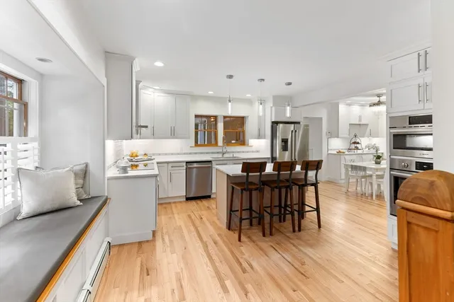 a living room with stainless steel appliances kitchen island granite countertop furniture and a wooden floor