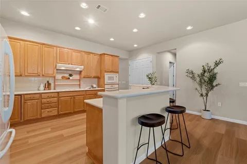 a kitchen with stainless steel appliances kitchen island granite countertop a table chairs and a refrigerator