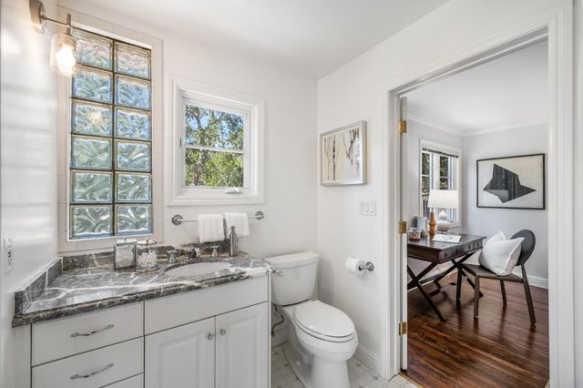 a bathroom with a granite countertop toilet a sink and a window