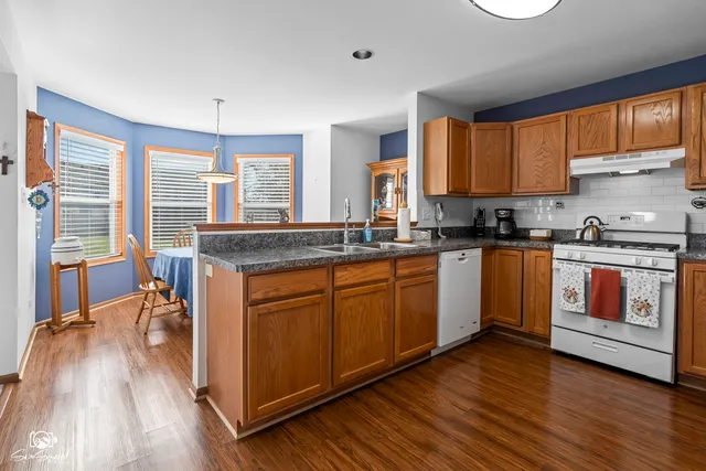 a kitchen with stainless steel appliances granite countertop wooden floors and white cabinets