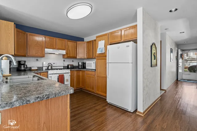 a kitchen with granite countertop wooden floors a refrigerator and a sink
