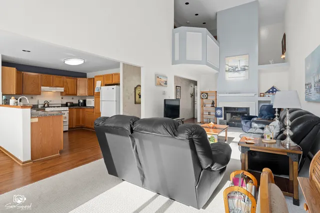a living room with furniture a fireplace kitchen view and a large window