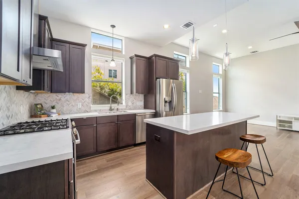 a kitchen with kitchen island granite countertop a sink stove and refrigerator