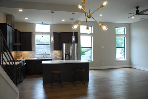 a kitchen with stainless steel appliances granite countertop a sink a stove a refrigerator cabinets and wooden floor