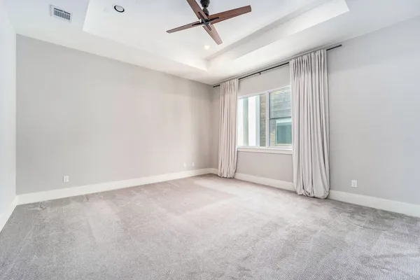 an empty room with windows and ceiling fan