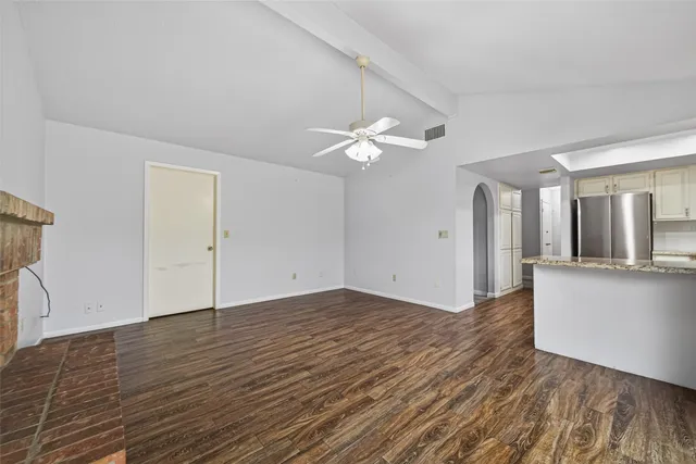an empty room with wooden floor and ceiling fan