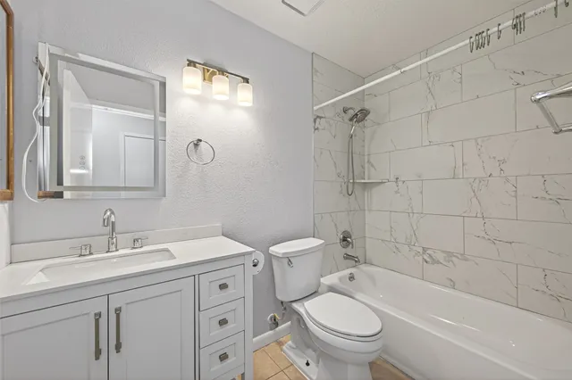 a bathroom with a granite countertop toilet a sink and a bathtub