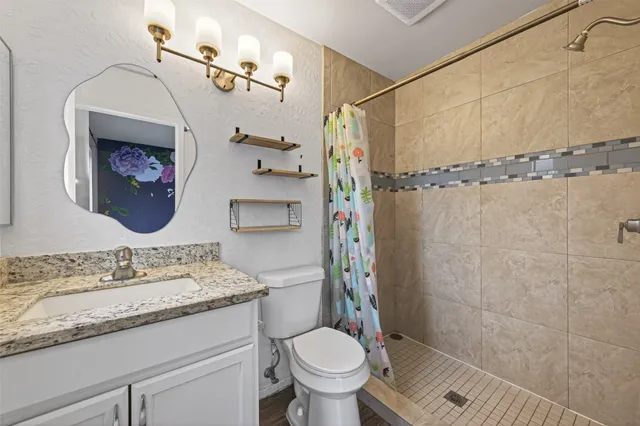a bathroom with a granite countertop sink a toilet and shower