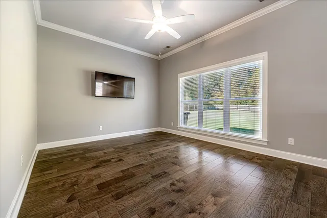 a view of empty room with wooden floor and fan
