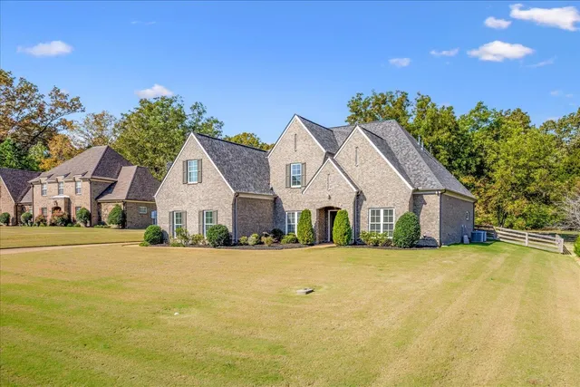 a front view of house with yard and trees in the background