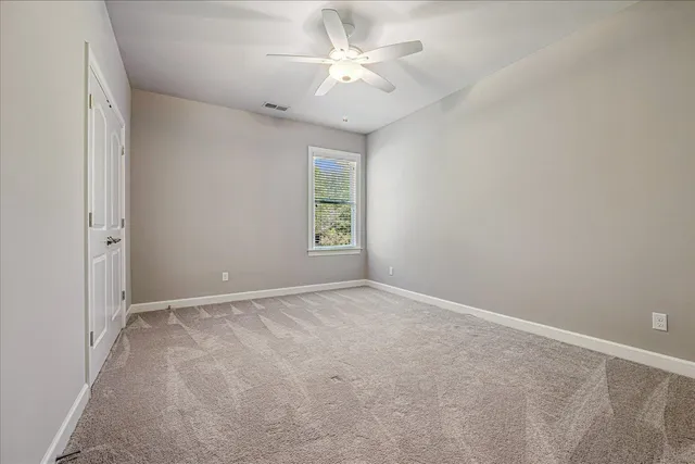 an empty room with windows and ceiling fan
