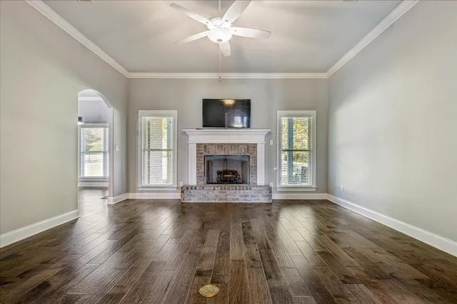 a view of an empty room with wooden floor fireplace and a window