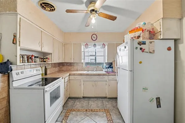 a kitchen with a refrigerator a sink and dishwasher with white cabinets
