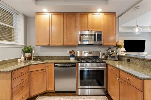 a kitchen with stainless steel appliances granite countertop a stove a sink and a microwave