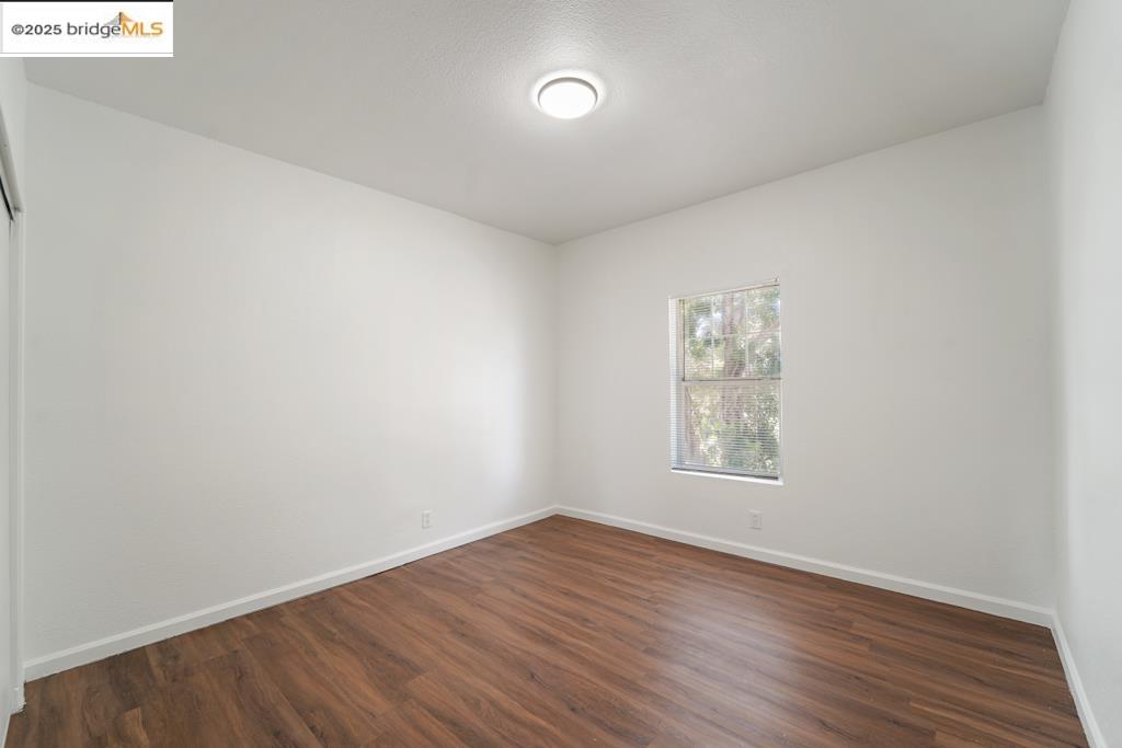 203 Bissell Avenue Richmond, CA 94801 - Photo 18 of 30 an empty room with wooden floor and windows