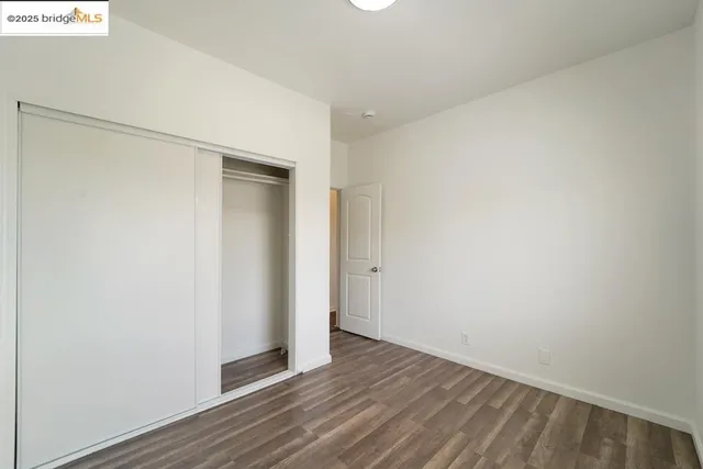 a view of an empty room with wooden floor and closet