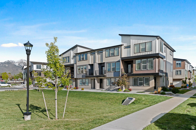 8307 Durham Street Sandy, UT 84070 - Photo 2 of 29 Modern townhome exterior featuring multi-toned siding, dark-framed windows, and a prominent mountain backdrop