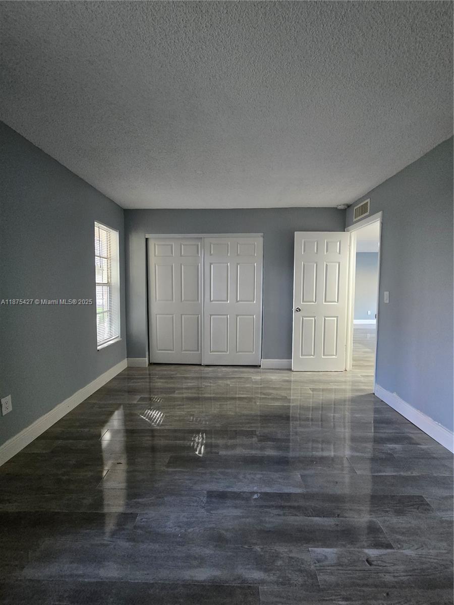 2800 Northwest 56th Avenue, Unit C104 Lauderhill, FL 33313 - Photo 13 of 17 a view of an empty room with wooden floor and a window