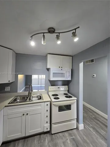 a kitchen with stainless steel appliances a stove a sink and white cabinets