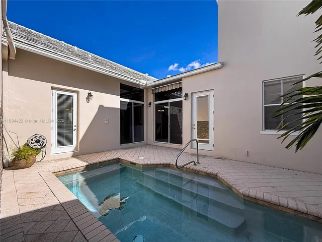 a view of pool with two chairs and a potted plant