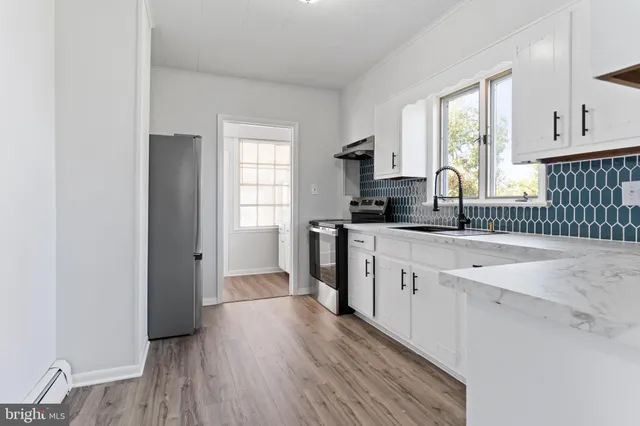 a kitchen with white cabinets and window