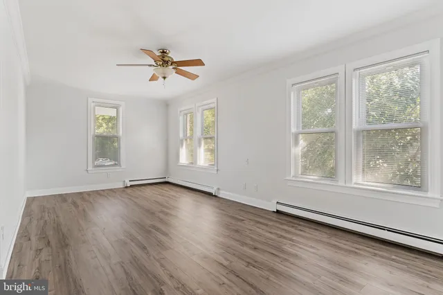a view of empty room with wooden floor and fan