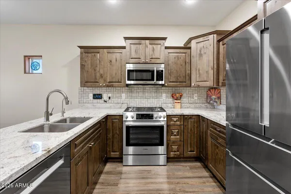 a kitchen with stainless steel appliances granite countertop a stove top oven a sink and a microwave