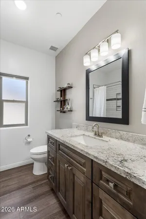 a bathroom with a granite countertop sink a toilet and mirror