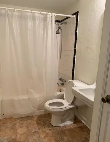 a white toilet sitting next to a shower curtain