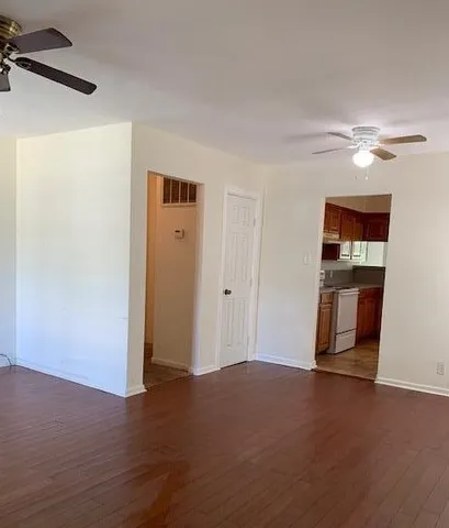 a view of empty room with wooden floor and fan