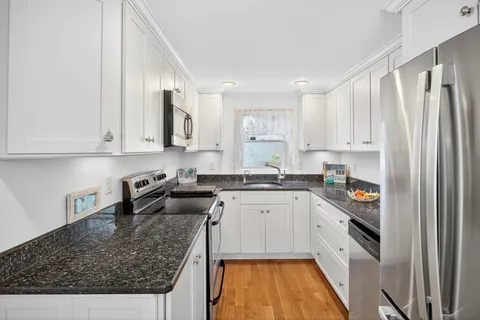 a kitchen with granite countertop a sink a stove and cabinets