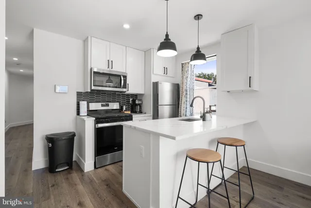 a kitchen with stainless steel appliances a stove a sink a refrigerator and a microwave