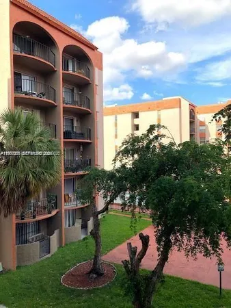 a front view of a multi story residential apartment building with yard and green space