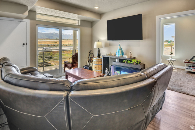 2101 North Main Street, Unit 306 Sunset, UT 84015 - Photo 7 of 22 Living area featuring sliding glass doors with transom windows, wood-finish flooring, and a built-in media console with a fireplace